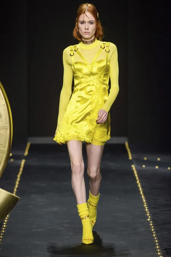 Желтое короткое шелковое платье, такого же цвета босоножки и длинные носки.