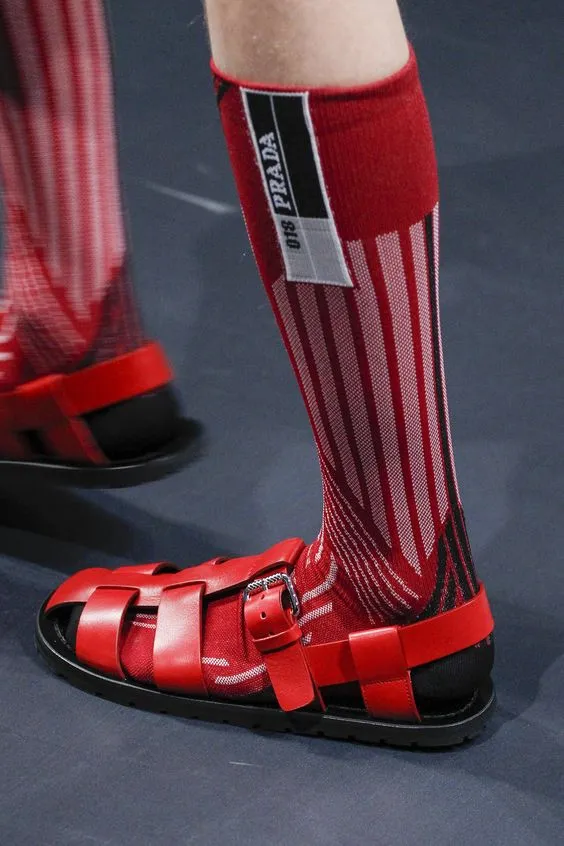 Сочетание красных кожаных мужских сандалий с бордовыми гольфами на показе Prada.