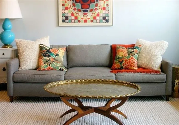 Серый однотонный диван можно дополнить цветными яркими подушками
