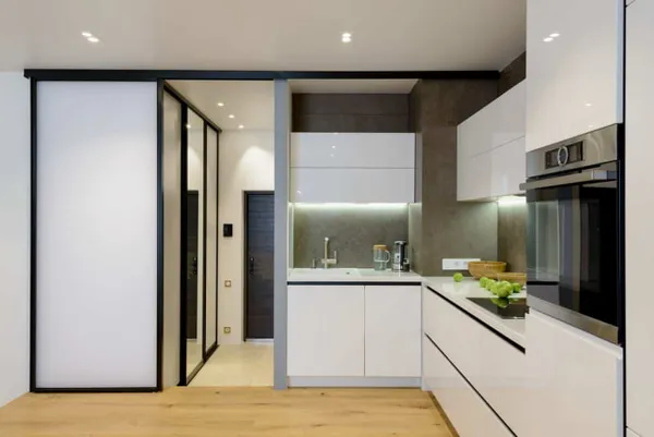 небольшая кухня с серыми стенами, светлым деревянным полом и белой мебелью